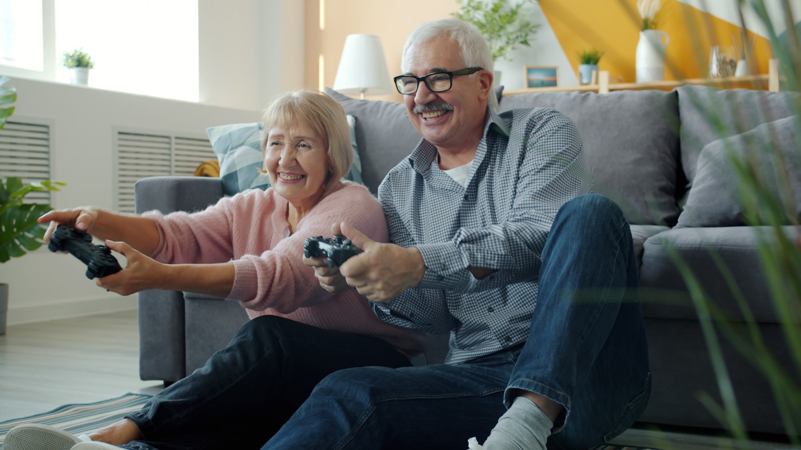 Elderly couple playing video games together on floor