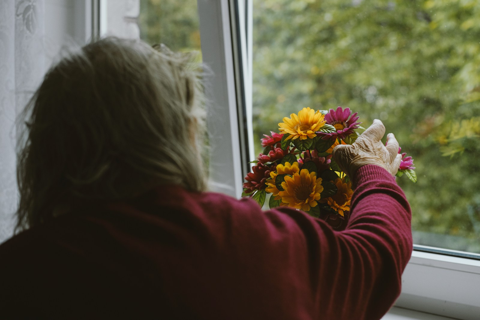 person in red long sleeve shirt holding yellow and white flower bouquet